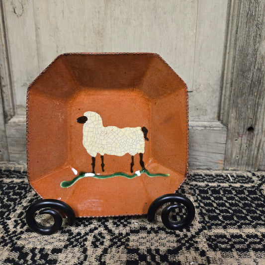Octagonal redware plate with sheep motif on a textured surface and a white background