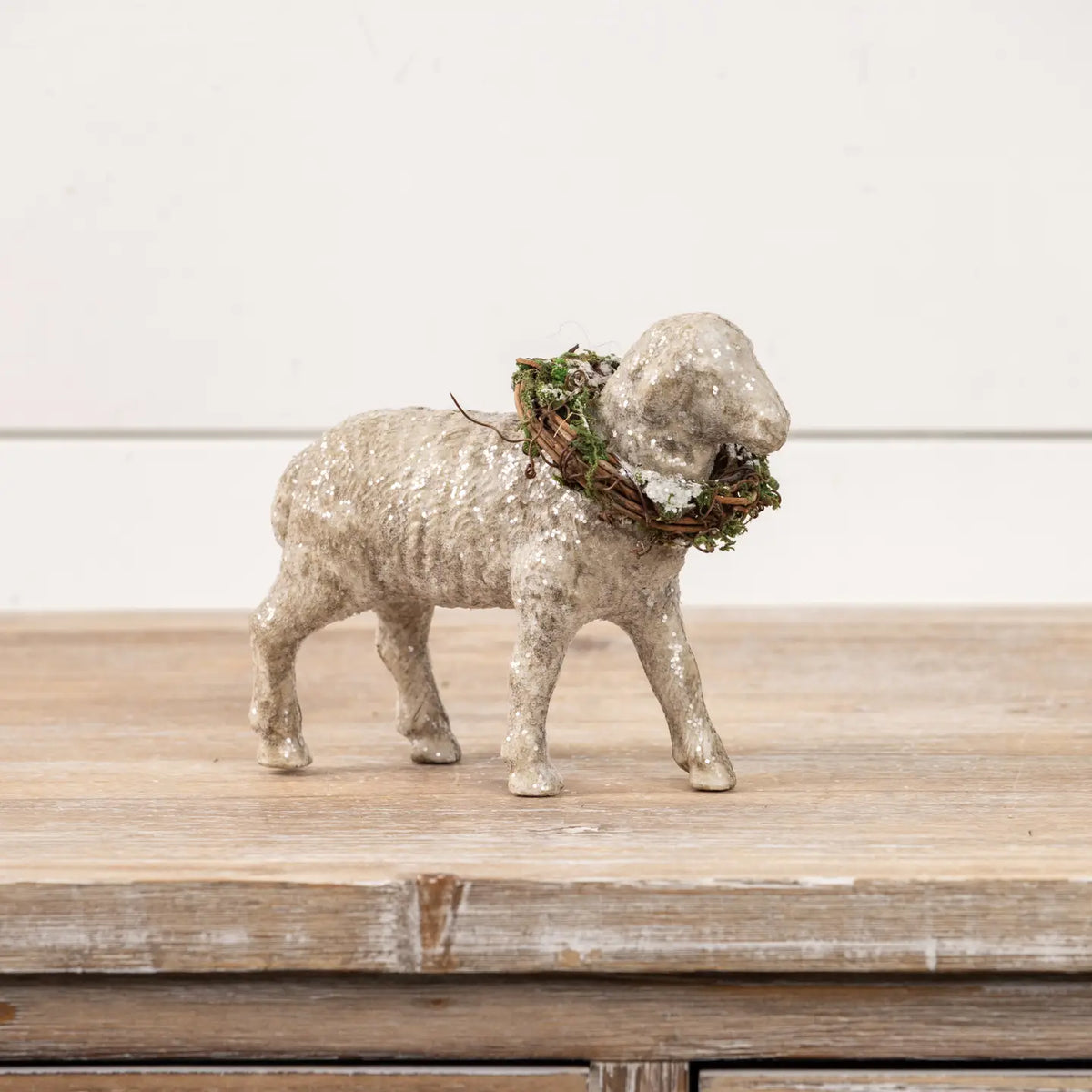 Decorative sheep figurine with a wreath on a wooden surface