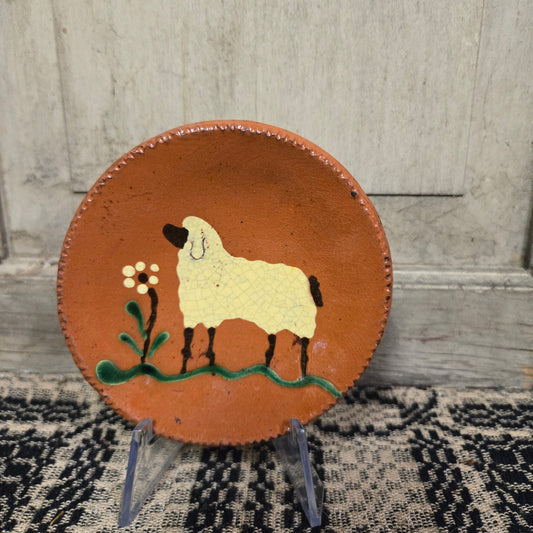 Small round redware plate with sheep and yellow flower motif