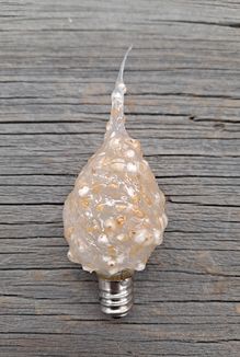 A 4 watt silicone scented bulb with a candelabra base, displaying a golden hue with a textured surface, placed on a wooden surface.