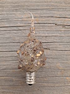 A clear silicone scented 4 watt bulb with a candelabra base, displayed on a wooden surface.
