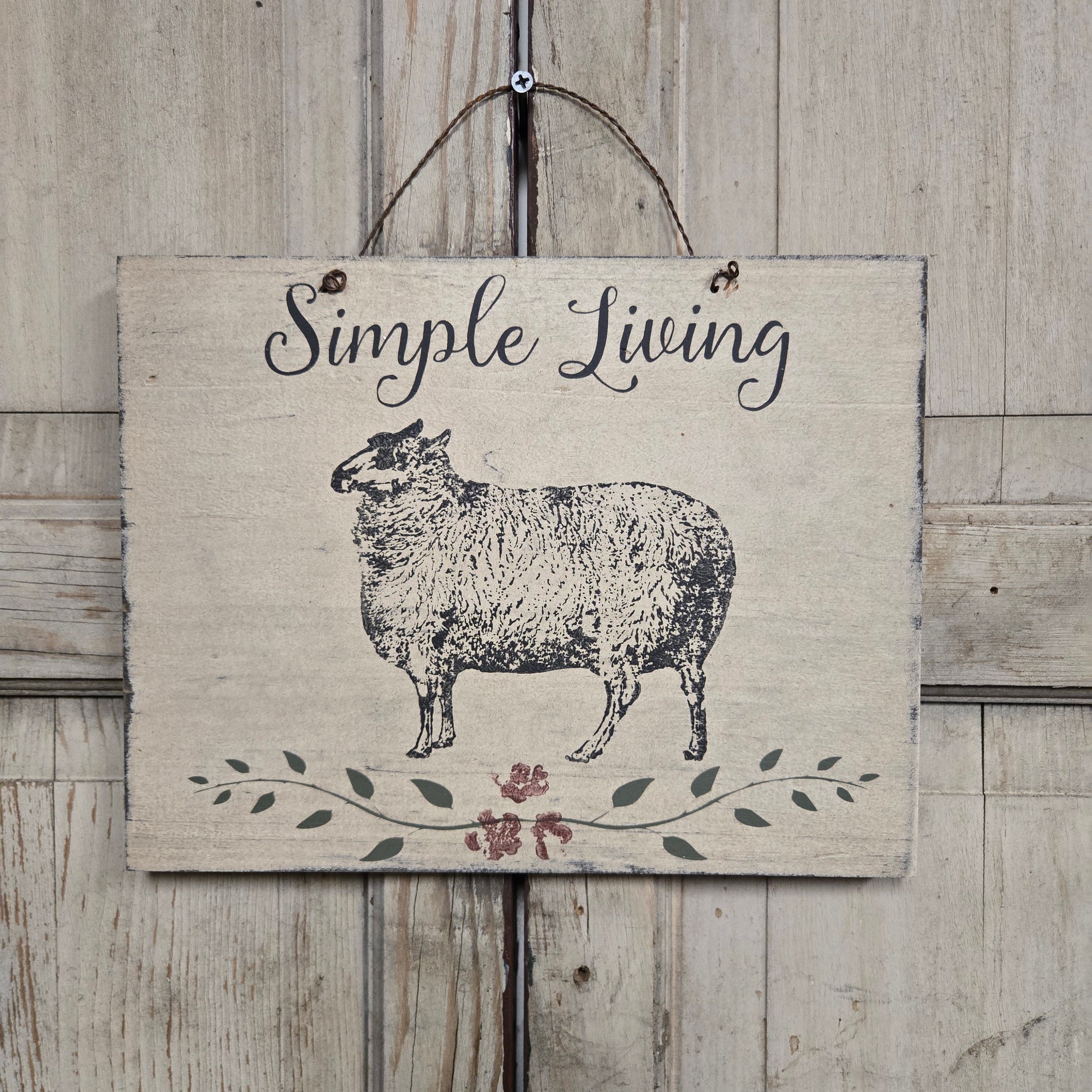 Decorative sign with a sheep illustration and 'Simple Living' text on a wooden background