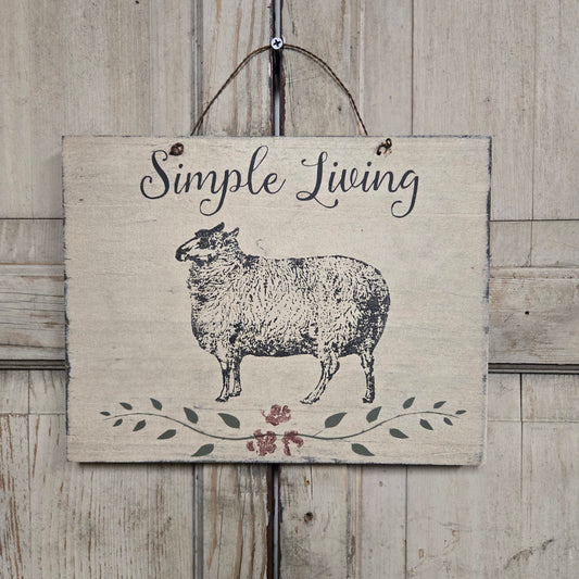 Decorative sign with a sheep illustration and 'Simple Living' text on a wooden background