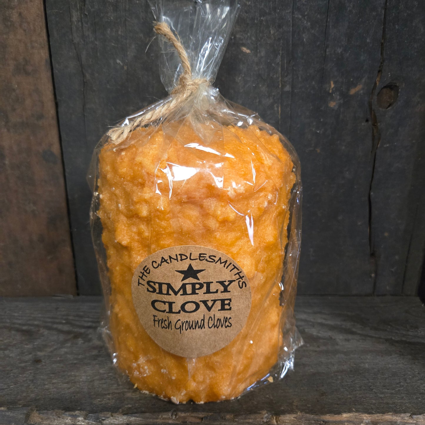 Packaged clove candle with a label on a wooden surface
