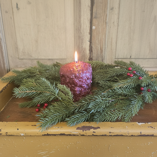 Candle in a decorative wreath on a wooden surface with a rustic background