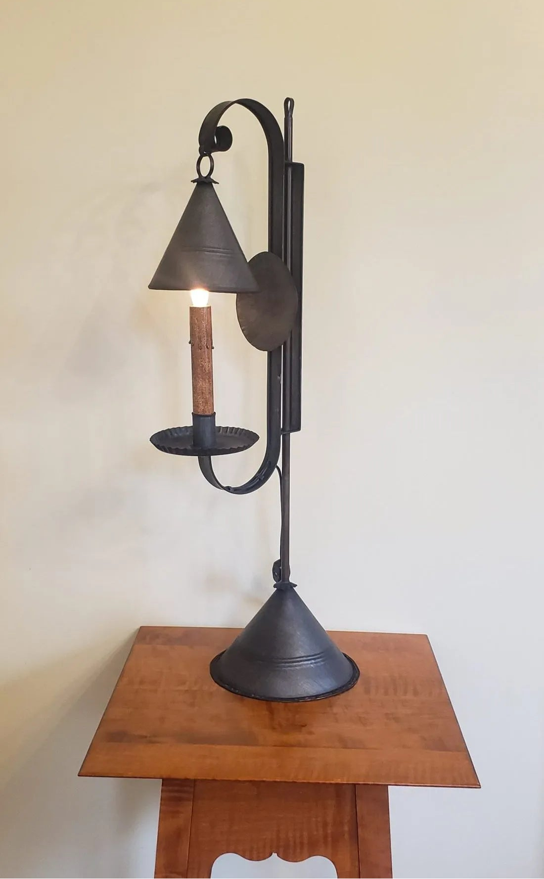 Decorative table lamp on a wooden stand against a plain wall