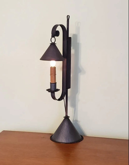 A black mini bell tin table lamp with a candle-like light source, placed on a wooden surface.