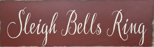 Wooden sign with 'Sleigh Bells Ring' text on a red-brown background