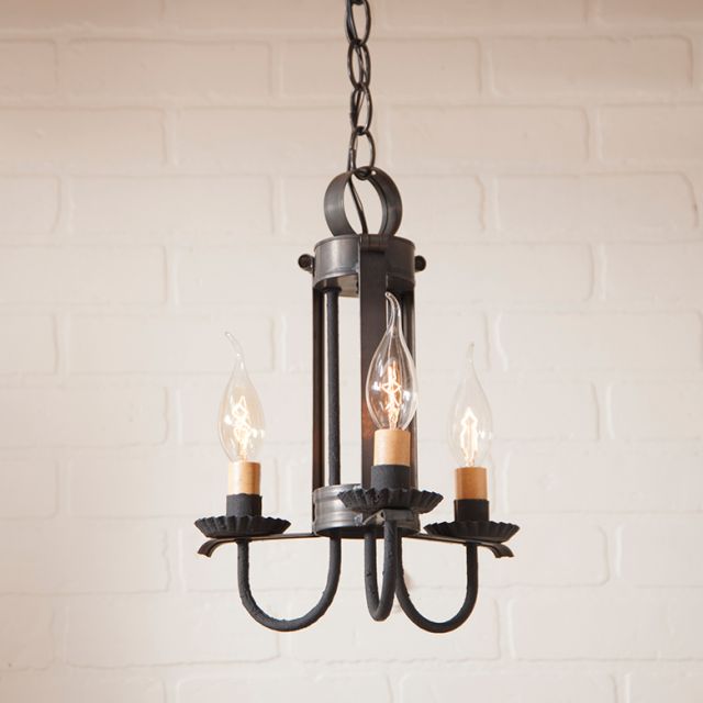 Vintage-style chandelier with three light bulbs against a white brick wall.