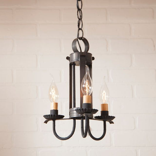 Vintage-style chandelier with three light bulbs against a white brick wall.
