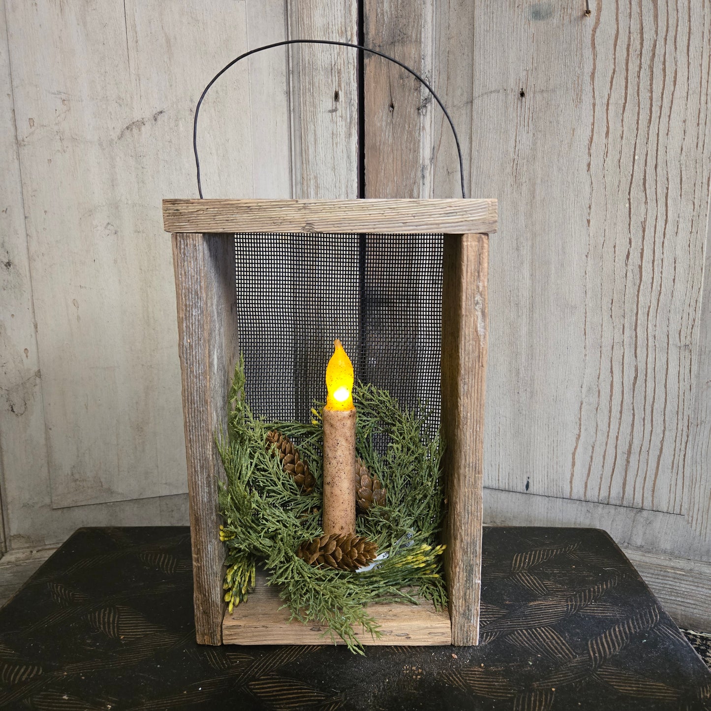 Wooden box with a candle and greenery on a wooden surface
