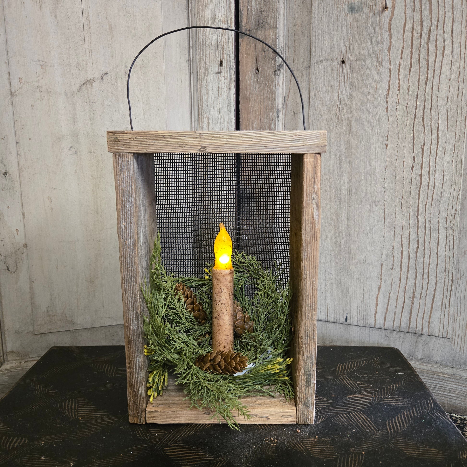 Wooden box with a candle and greenery on a wooden surface