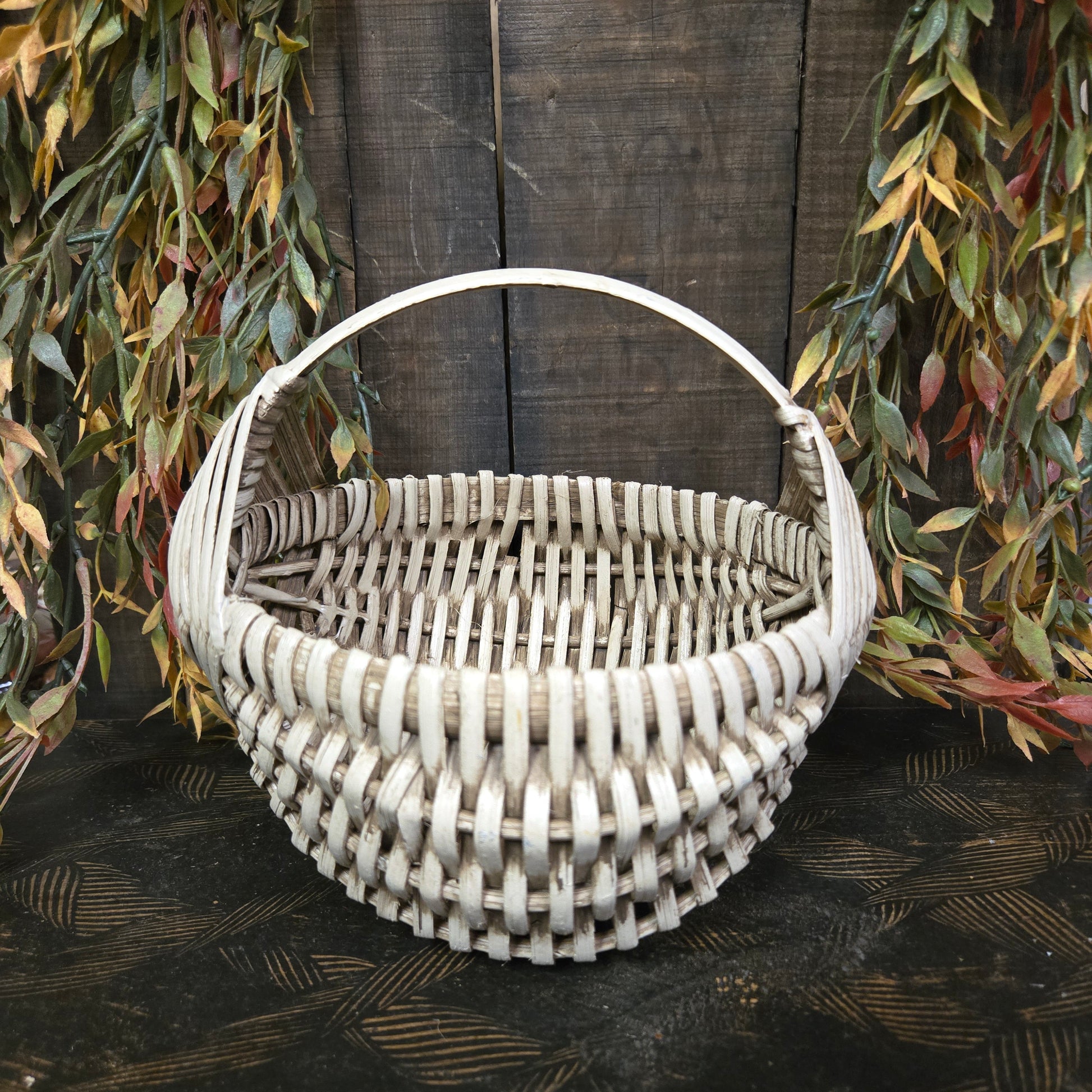 Handwoven basket sitting against a wooden wall with greenery