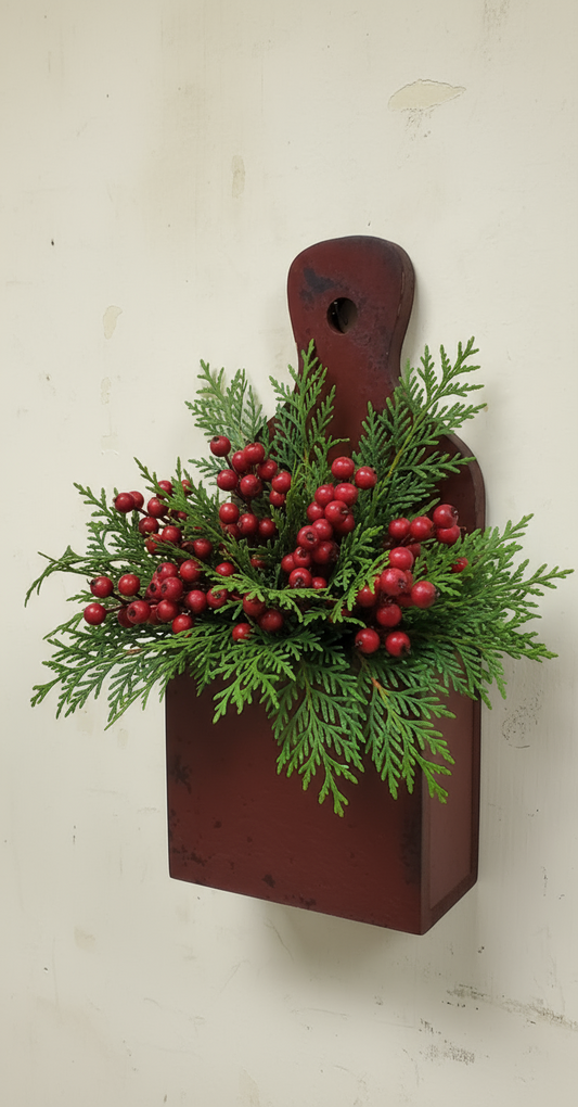 Decorative wall piece with greenery and red berries on a wooden board against a white background