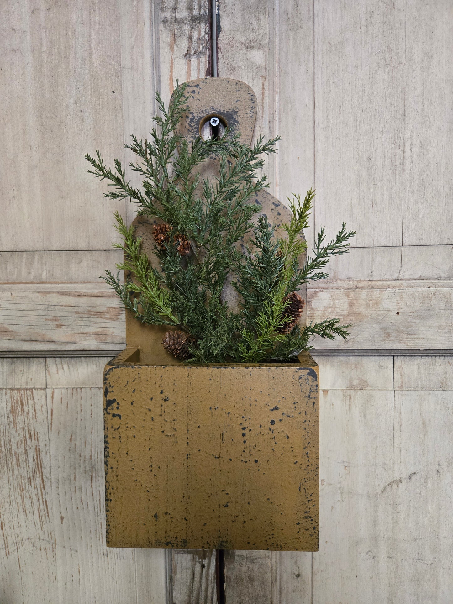 Decorative arrangement of greenery and pinecones on a textured surface