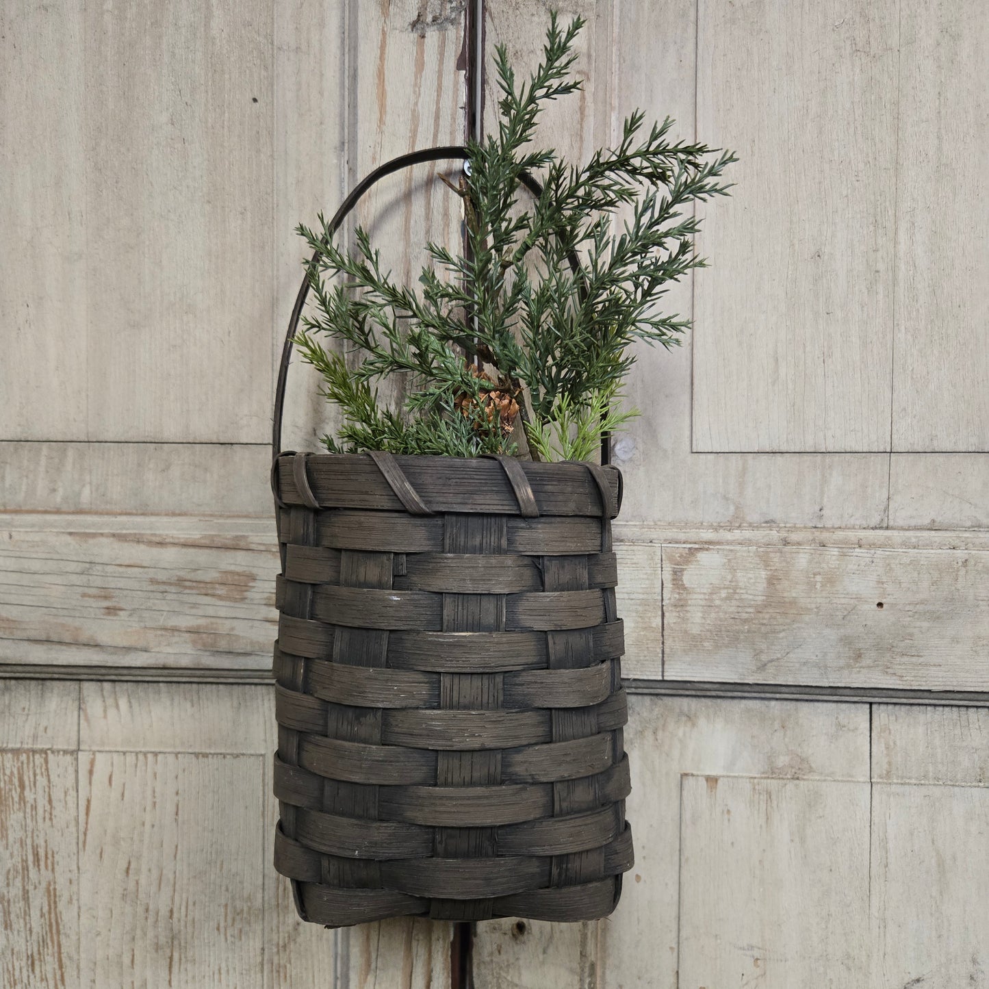 Woven basket with greenery on a wooden surface