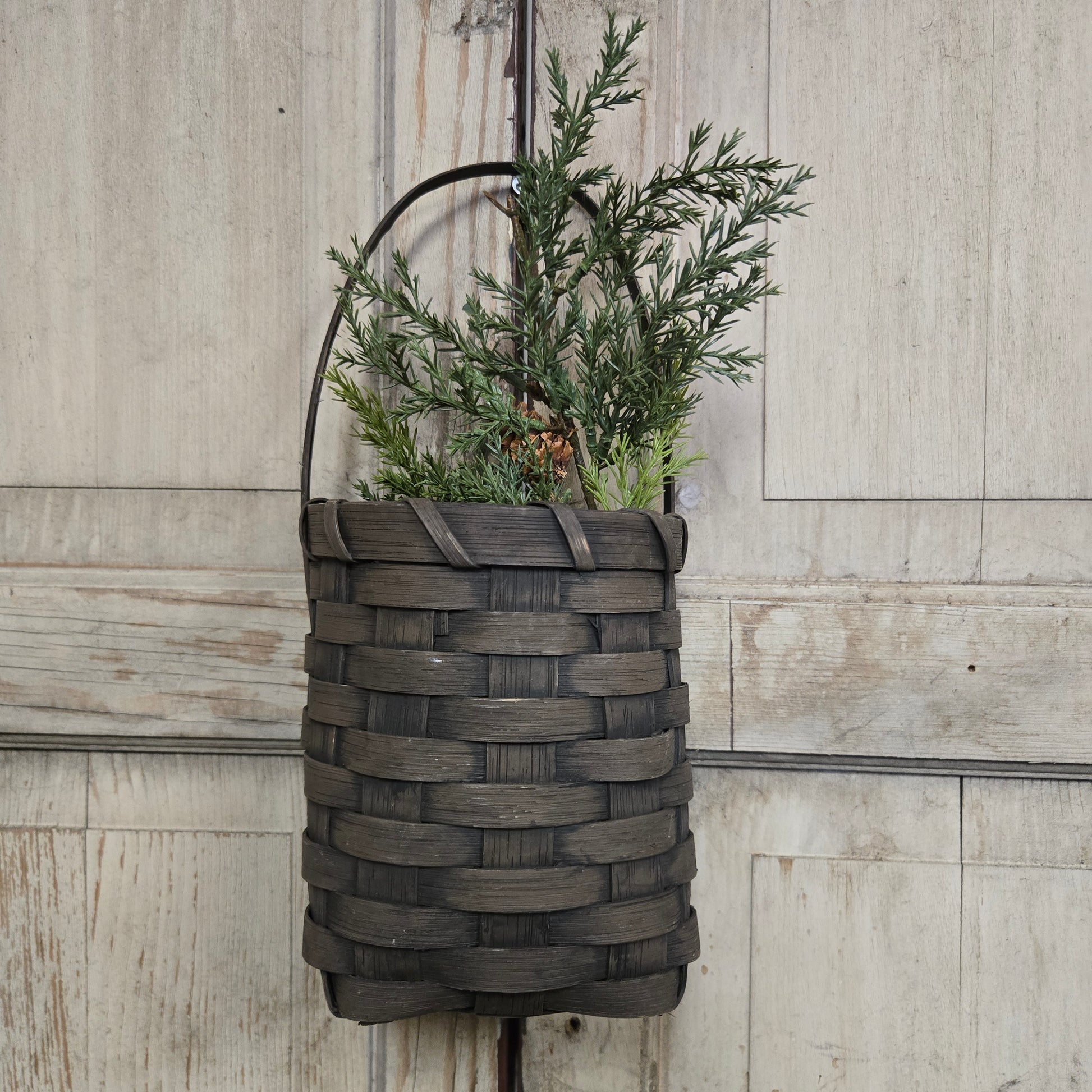 Woven basket with greenery on a wooden surface