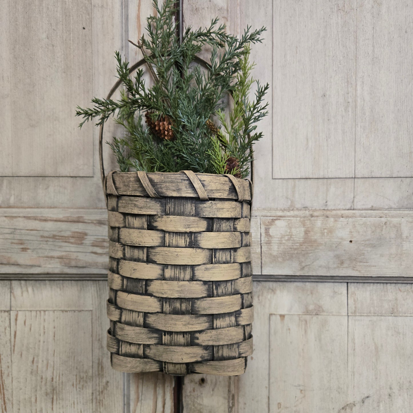Woven basket with greenery on a wooden surface