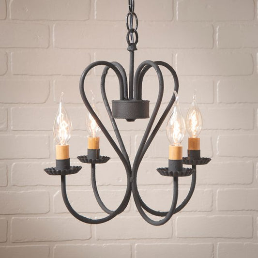 A textured black chandelier with a heart-shaped design, featuring four candle-like light fixtures hanging from its arms.