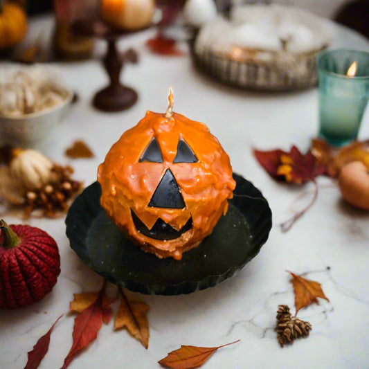 Halloween-themed cupcake with jack-o'-lantern face on a textured surface