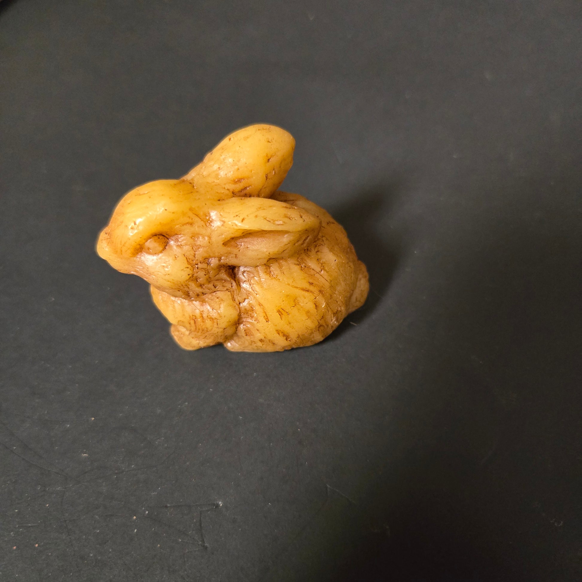 Beeswax rabbit sculpture on a dark gray background