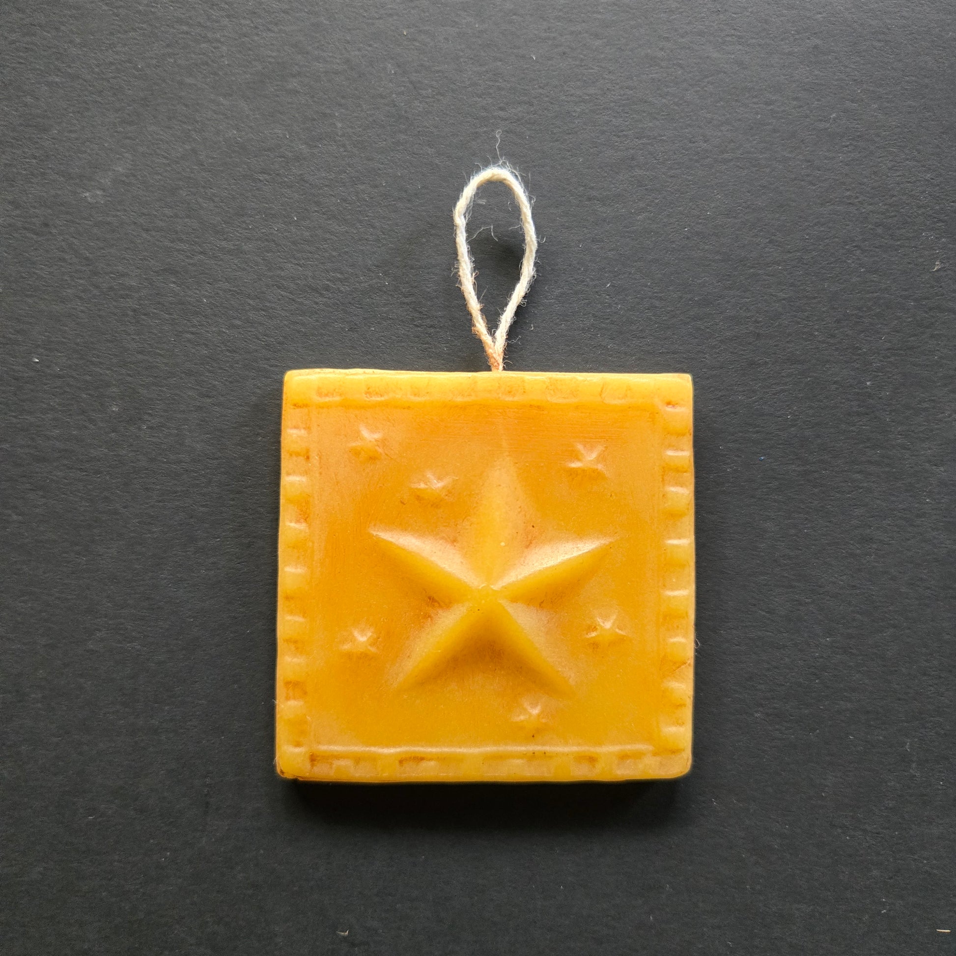 Square beeswax block with star pattern on a dark background