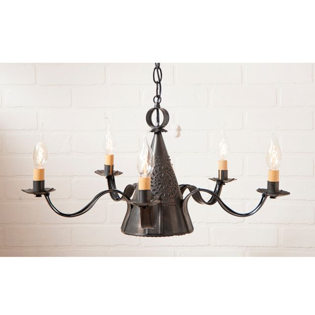 Black chandelier with five candle-style lights on a white brick wall background