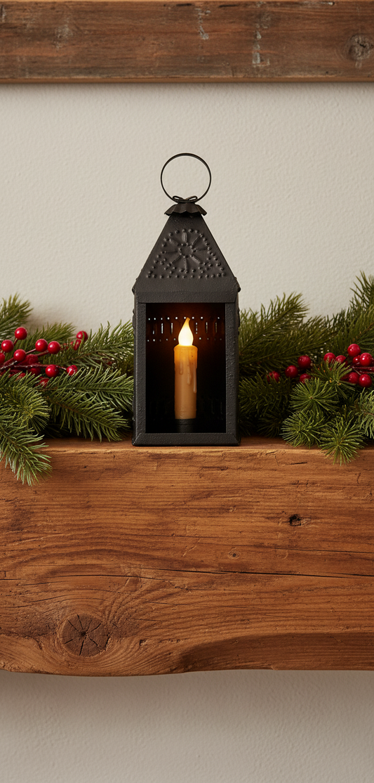 Black lantern with a lit candle on a wooden shelf with greenery and berries.