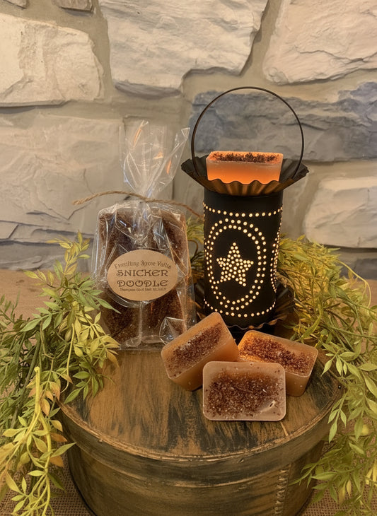 Decorative display with tarts, a tart warmer, and greenery against a stone wall.