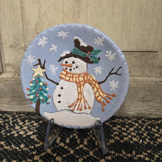 Vibrant blue redware plate with snowman putting a star on top of a Christmas tree