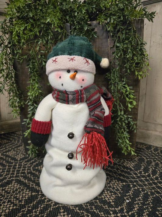 A snowman figurine with  a colorful hat and scarf on a decorative background.