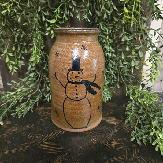 Decorative stoneware crock with a snowman design on a green leafy background
