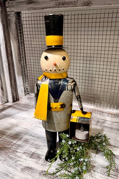 A decorative snowman figure with a lantern, wearing a black and yellow scarf, and a top hat.