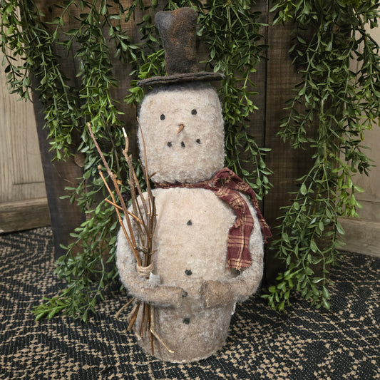 Decorative snowman figure with a plaid scarf against a green leafy background