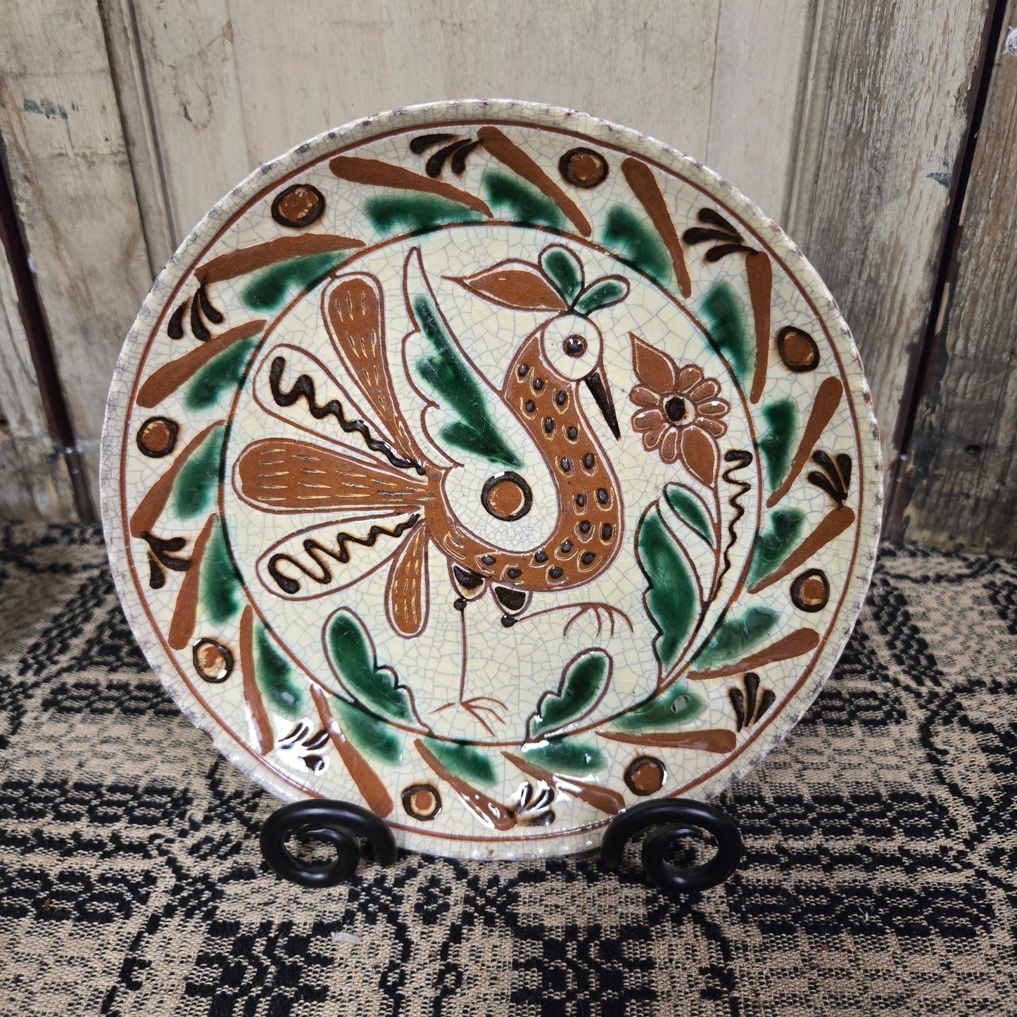 Redware plate with speckled bird and flower with an intricate border