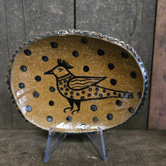 Decorative plate with black polka dots and a central design on a wooden surface