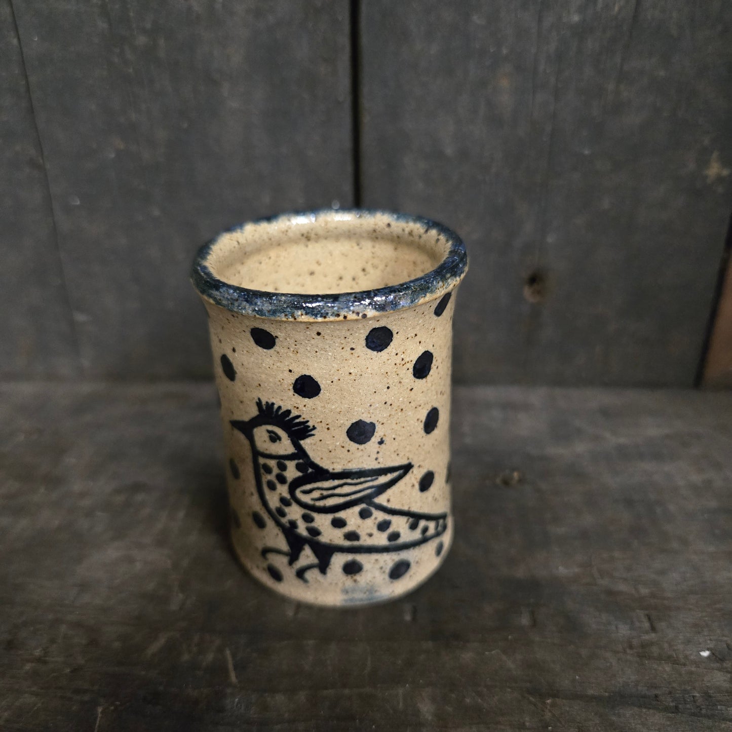 Cylindrical ceramic product with black patterns on a wooden surface