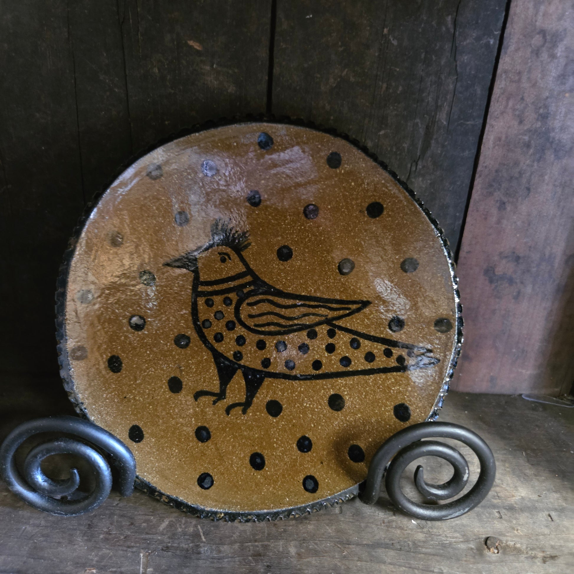 Decorative stoneware with a bird design and spiral patterns on a wooden surface