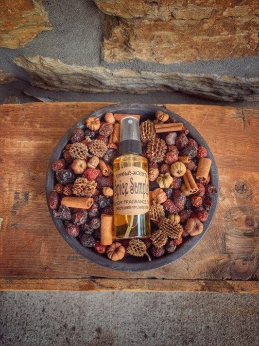 A metal pan with a bottle labeled 'Spice Sampler Tindle' surrounded by potpourri and cinnamon sticks.