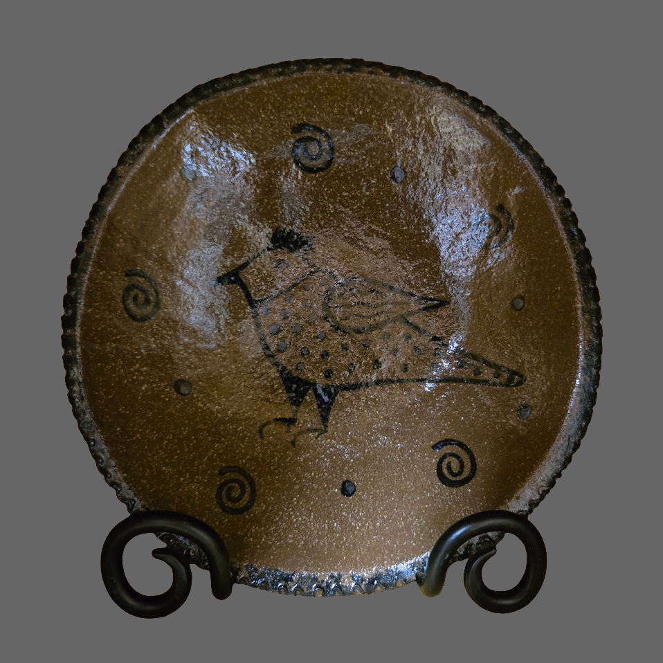 A round stoneware plate featuring a spotted bird motif with a squiggle border
