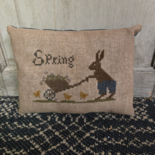 Rectangular cross stitch pillow with a bunny and a wagon