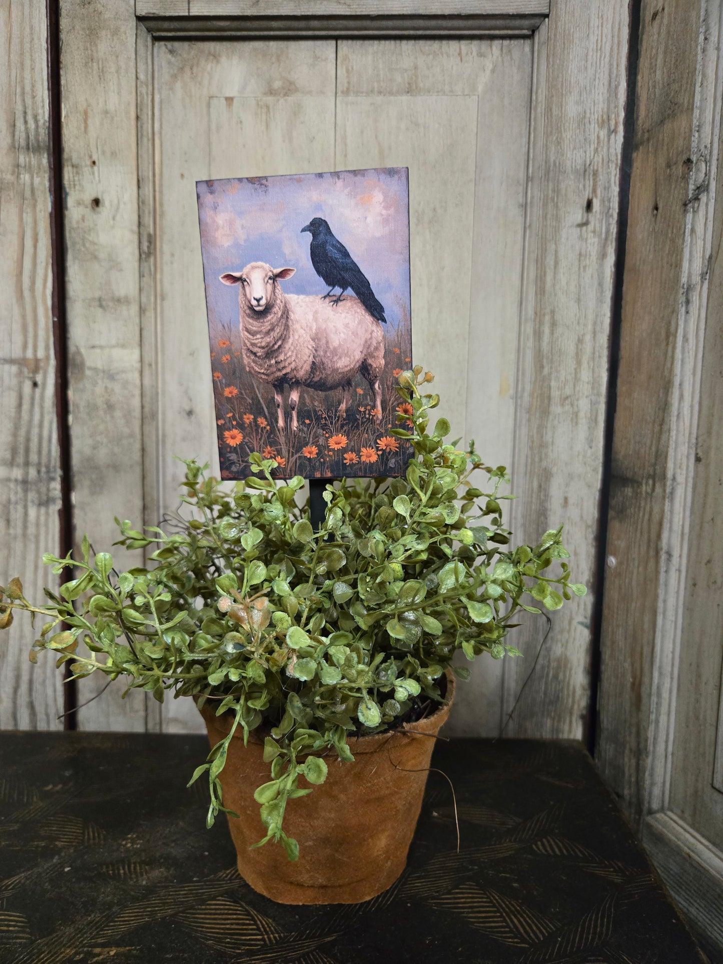 Potted plant with a picture of a sheep on a plant poke.