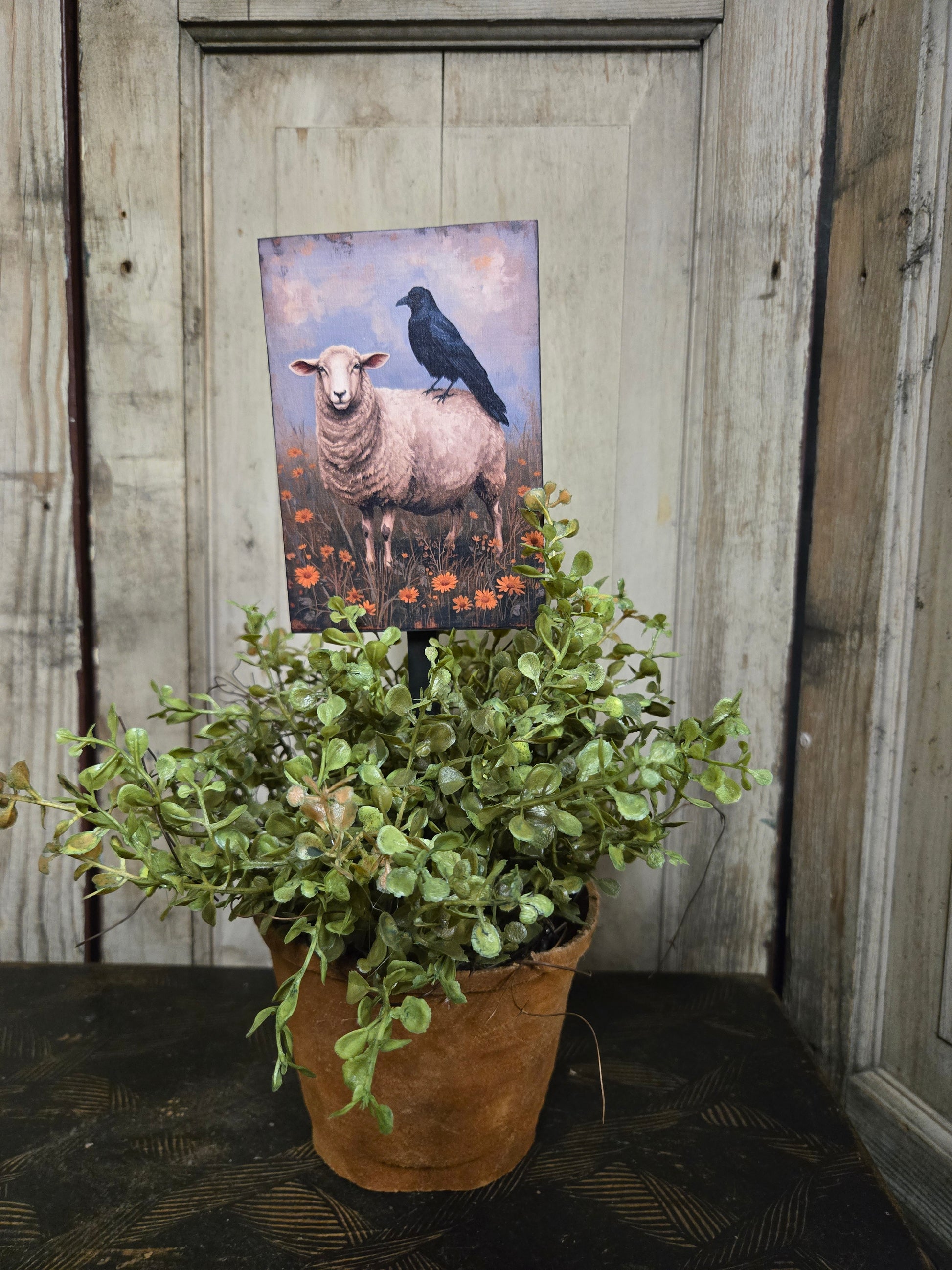 Potted plant with a picture of a sheep on a plant poke.