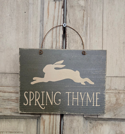 Wooden sign with a rabbit silhouette and 'Spring Thyme' text on a rustic wooden background