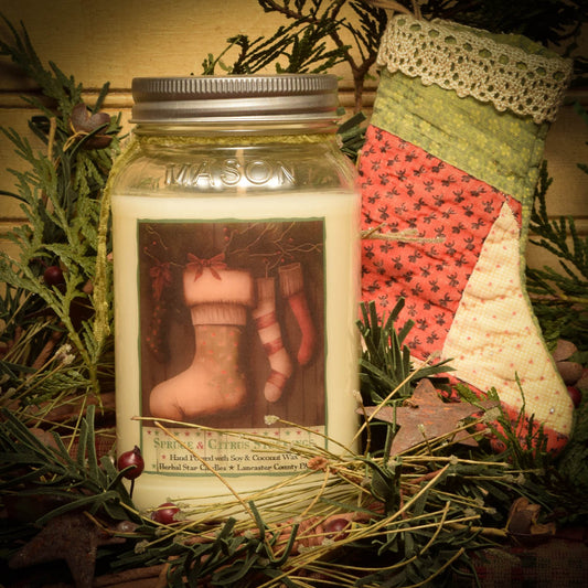 A 24 oz mason jar candle with a 'Spruce and Citrus' scent, placed inside a decorative stocking with Christmas-themed decorations.