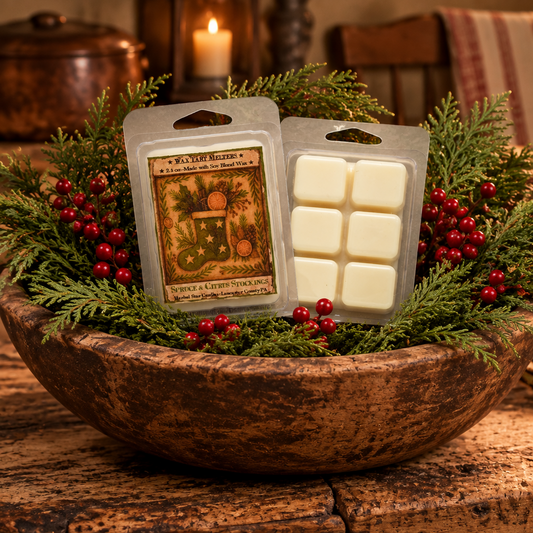 Two wax melts packages labeled 'Winter & Holiday Stocking' displayed in a rustic wooden bowl filled with greenery and red berries on a wooden table, with a warm indoor background.