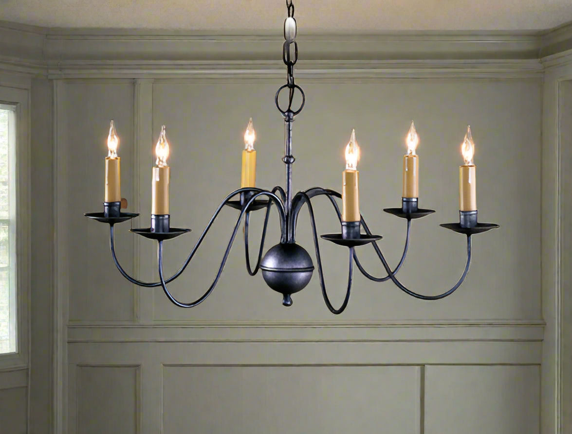 A traditional-style wrought iron chandelier with six light fixtures, displayed against a wooden backdrop.