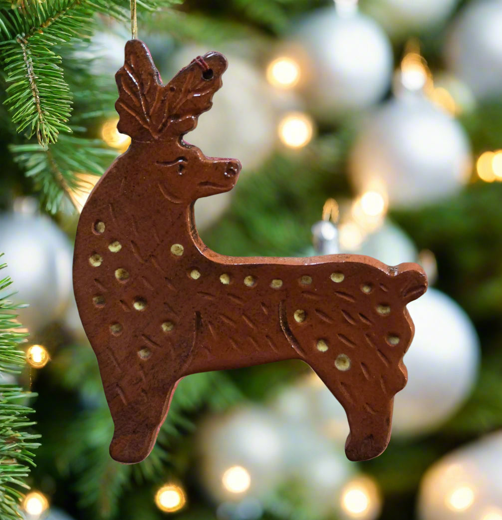Decorative deer ornament hanging on a Christmas tree with blurred lights in the background