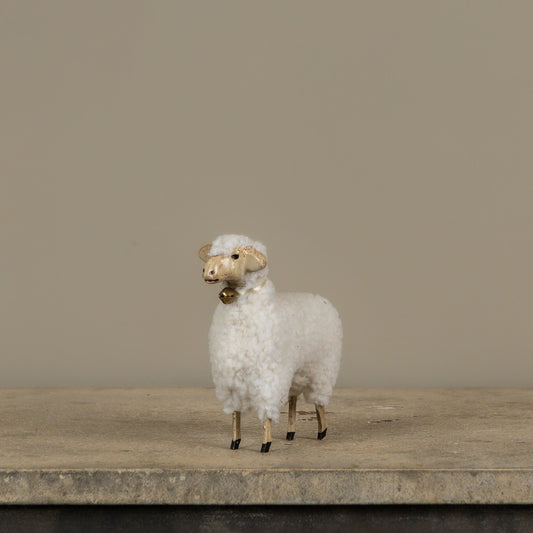 White sheep figurine on a wooden surface with a plain background