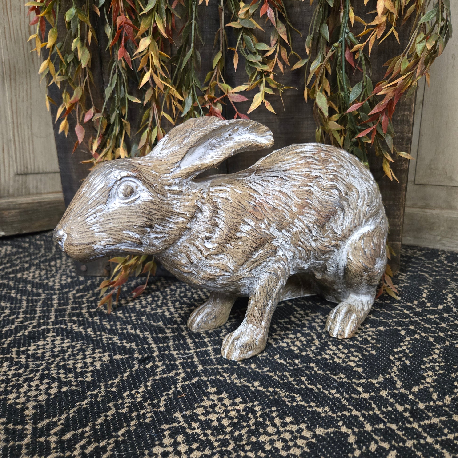 Decorative rabbit figurine on a textured surface with foliage